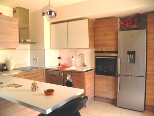 une cuisine avec des appareils en acier inoxydable et des armoires en bois dans l'établissement Belle villa moderne avec piscine, 800m plage, parking privé et clim, idéale pour familles à Sète - FR-1-338-31, à Sète