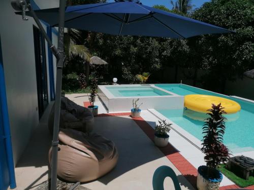 a pool with an umbrella and a swimming pool at Villa Jana, Bantayan, Santa Fe in Bantayan Island