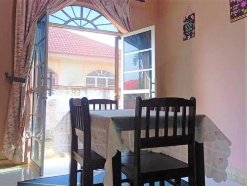 uma mesa de jantar com 2 cadeiras e uma janela em Nafili homestay 3bd 2br em Kota Bharu