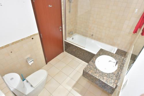 a bathroom with a toilet and a sink and a tub at The beach hostel Dubai in Dubai
