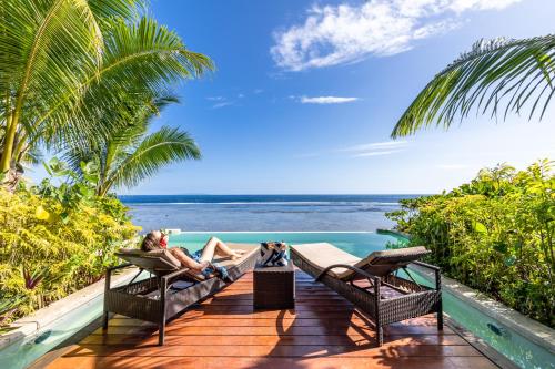 a couple sitting on the deck of a resort with the ocean at Savasi Island Resort in Savusavu