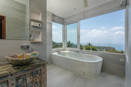 La salle de bains est pourvue d'une grande baignoire et d'une grande fenêtre. dans l'établissement Takian Villa : vue mer et coucher de soleil, à Salad Beach