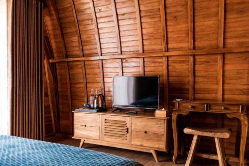 a tv on a wooden dresser in a bedroom at Kabinku Bali in Bedugul