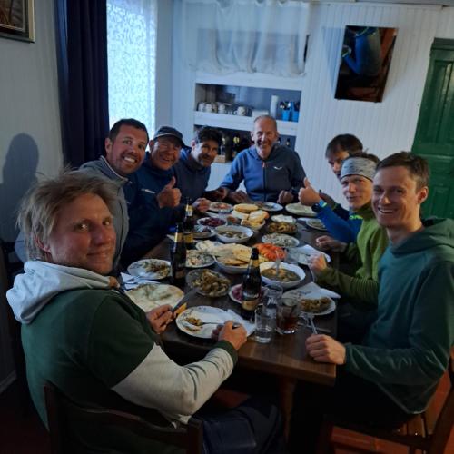 a group of people sitting around a table eating food at Chvibiani Guesthouse & Bar in Ushguli
