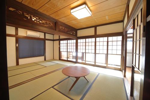 a room with a table in a room with windows at 釣りスポットの松部漁港まで徒歩1分-ファミリー&釣り好きに大人気の宿 in Katsuura