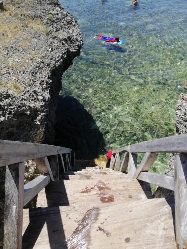 a wooden bridge over the water with people swimming in the water at Almare Guest House Siquijor in San Juan