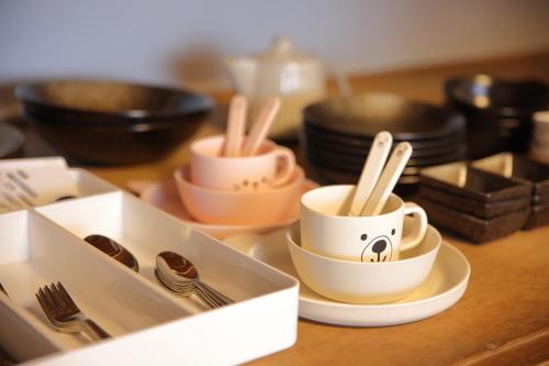 a table topped with cups and plates and utensils at 釣りスポットの松部漁港まで徒歩1分-ファミリー&釣り好きに大人気の宿 in Katsuura