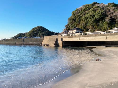 a bridge over a beach next to the water at 釣りスポットの松部漁港まで徒歩1分-ファミリー&釣り好きに大人気の宿 in Katsuura