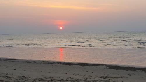 a sunset on the beach with the ocean in the background at Paradis Villa B3 in Ko Kho Khao