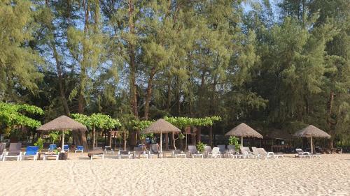 a group of chairs and umbrellas on a beach at Paradis Villa B3 in Ko Kho Khao