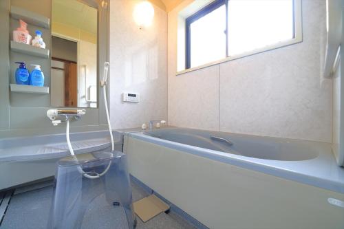 a bathroom with a tub and a sink and a mirror at 釣りスポットの松部漁港まで徒歩1分-ファミリー&釣り好きに大人気の宿 in Katsuura