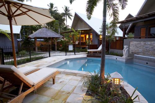 a swimming pool with a chair and an umbrella at Pure Magnetic Villa 6 in Nelly Bay