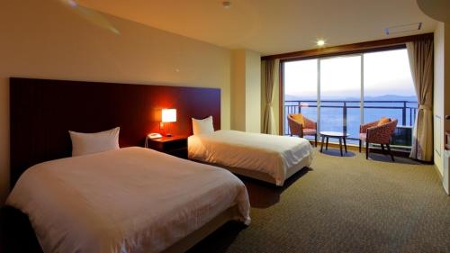 a hotel room with two beds and a large window at Yunoko Umi To Yuyake in Minamata