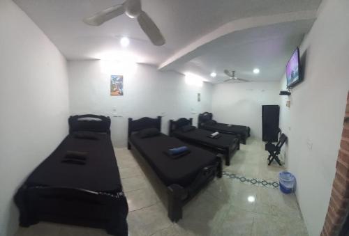 Habitación con sofás negros y TV de pantalla plana. en HOSTAL EL BALCONCITO en Cartagena de Indias