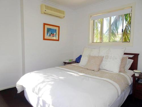 1 cama blanca en un dormitorio con ventana en Sea Views at Aqualuna 9 Solitary Islands Way 94, en Coffs Harbour