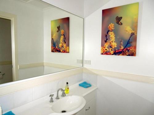 baño con lavabo y 2 pinturas en la pared en Sea Views at Aqualuna 9 Solitary Islands Way 94, en Coffs Harbour