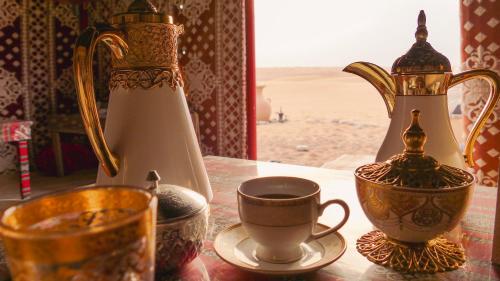 a table with cups and tea pots on top of a table at Starwatching Private Camp in Ḩawīyah