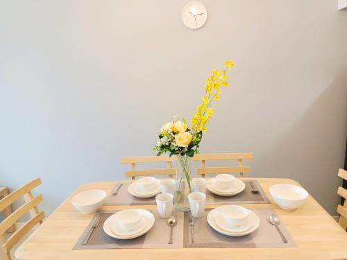 a wooden table with plates and a vase of flowers at Medini Elysia Park , 3 min to Legoland, Netflix By Hint Homestay in Nusajaya