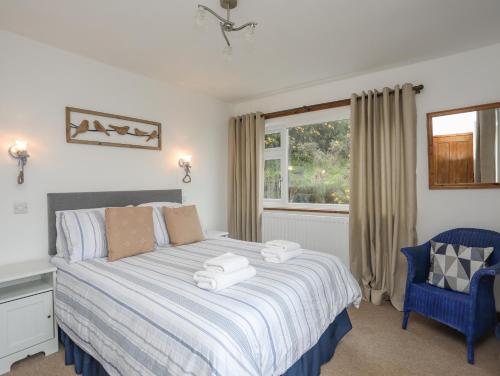 a bedroom with a bed with a blue chair and a window at Cottage in Pwllheli