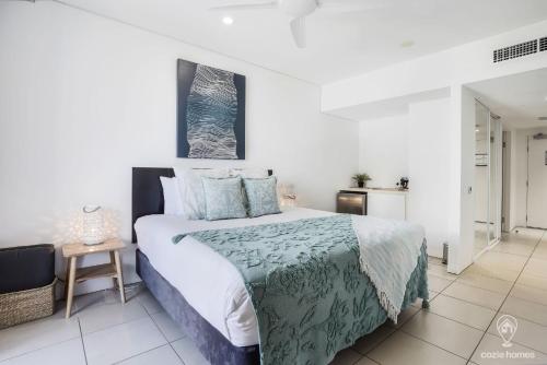 a bedroom with a bed with a green and white comforter at 602 Harbour Lights in Cairns