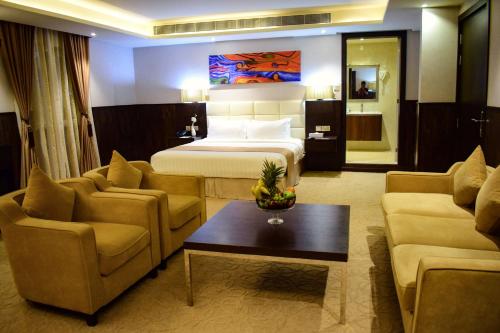 a hotel room with a bed and two couches at The Secure Inn Hotel Muscat in Muscat