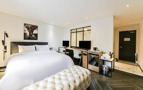 een slaapkamer met een groot wit bed en een bureau bij KAMA Hotel in Jeonju