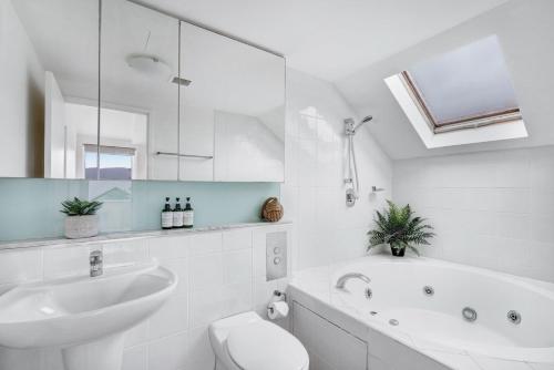 a bathroom with a sink and a tub and a toilet at The Lookout at Iluka Resort Apartments in Palm Beach