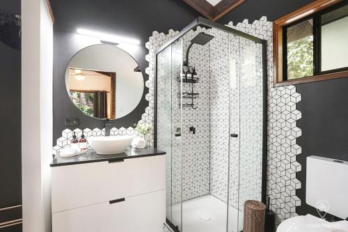 a bathroom with a shower with a sink and a mirror at Bindi Treehouse - Elevated Pole Home in Freshwater