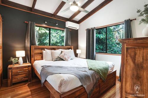 a bedroom with a large bed and two windows at Bindi Treehouse - Elevated Pole Home in Freshwater