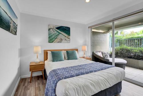 a bedroom with a large bed and a balcony at Poolside at Iluka Resort Apartments in Palm Beach