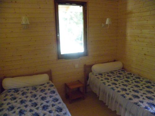 two beds in a room with a window at Le Chalet du Chloris in Saint-Maxire