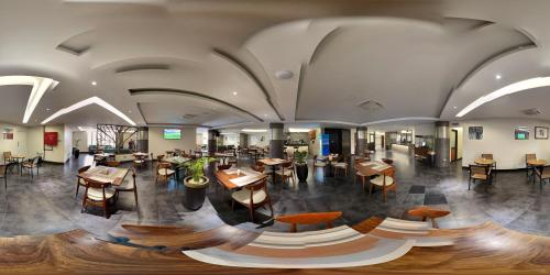 a restaurant with tables and chairs in a building at Victoria Mews Hotel in Kampala
