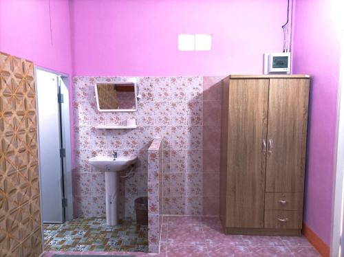 baño con paredes de color rosa, lavabo y espejo en Vimanmek Resort en Yasothon