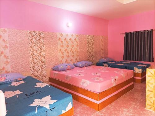 two beds in a room with pink and purple walls at Vimanmek Resort in Yasothon