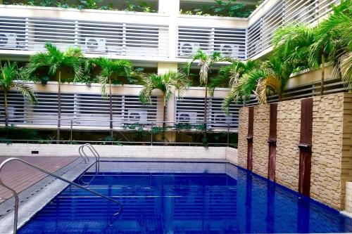 uma piscina em frente a um edifício com palmeiras em Condotel at 150 Newport Blvd. near NAIA T3 w/ Wifi em Manila