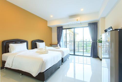 two beds in a hotel room with a balcony at CHANAPAT APARTMENT in Chiang Mai