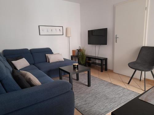 ein Wohnzimmer mit einem blauen Sofa und einem TV in der Unterkunft ApartNet Apartamenty przy Promenadzie in Świnoujście