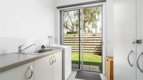 a kitchen with a sink and a sliding glass door at Anchorage in Apollo Bay