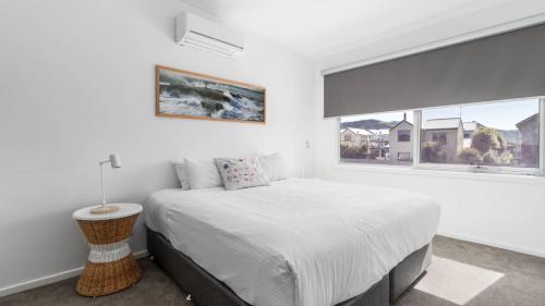 a white bedroom with a bed and a window at Anchorage in Apollo Bay