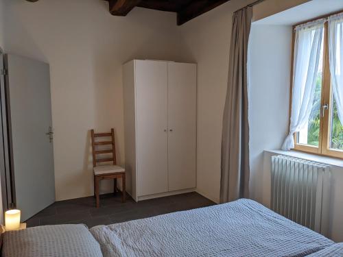 a bedroom with a bed and a chair next to a window at Casa Ai Portici in Gordola
