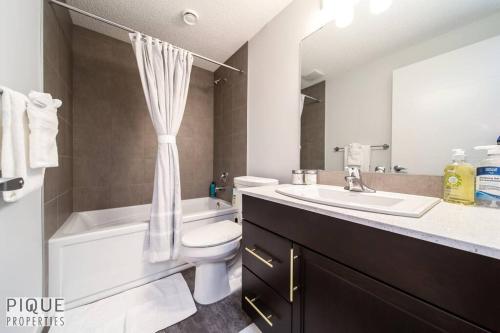 a bathroom with a sink and a toilet and a bath tub at NEW Modern 2 Bedroom Suite, Complimentary Netflix, Sleeps 4 in Edmonton