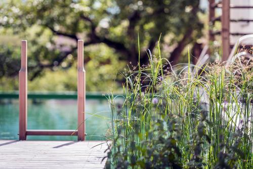 a wooden dock with a chair and some tall grass at Das Urgestein in Stans