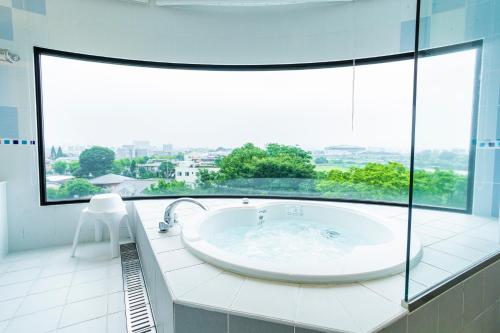 un ampio bagno con vasca e ampia finestra di Hotel Sanderson a Maebashi