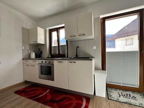 a kitchen with white appliances and a large window at APARTMA ALMA in Bovec