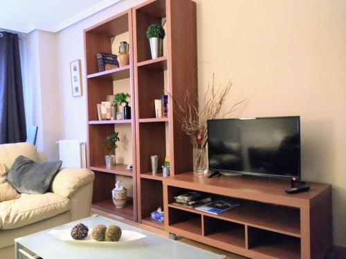 uma sala de estar com televisão num centro de entretenimento em madeira em Apartamento en OVIEDO,WIFI em Oviedo