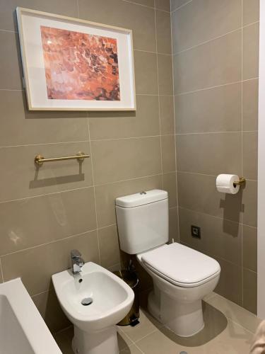 a bathroom with a white toilet and a sink at Intempo privat luxury apartment & spa in Benidorm