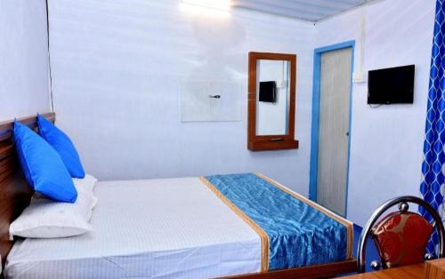 a bedroom with a bed with blue pillows and a mirror at Blackcherry Munnar in Munnar