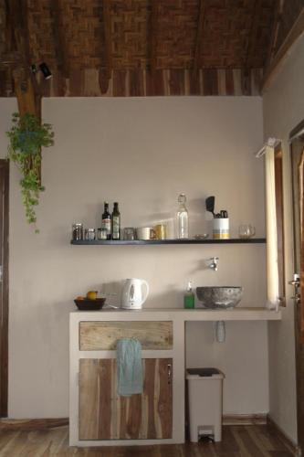 a kitchen with a counter with a sink and shelves at Santai House in Tetebatu