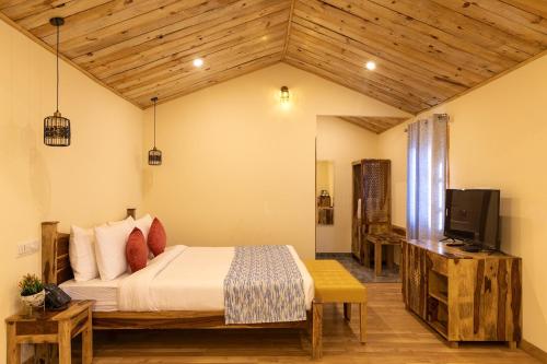 a bedroom with a bed and a flat screen tv at Aaroham Resort Shimla ! Luxury Cottage by Aamod Group in Shimla
