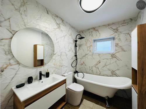 een badkamer met een wit bad, een wastafel en een spiegel bij magic bricks in Zalău